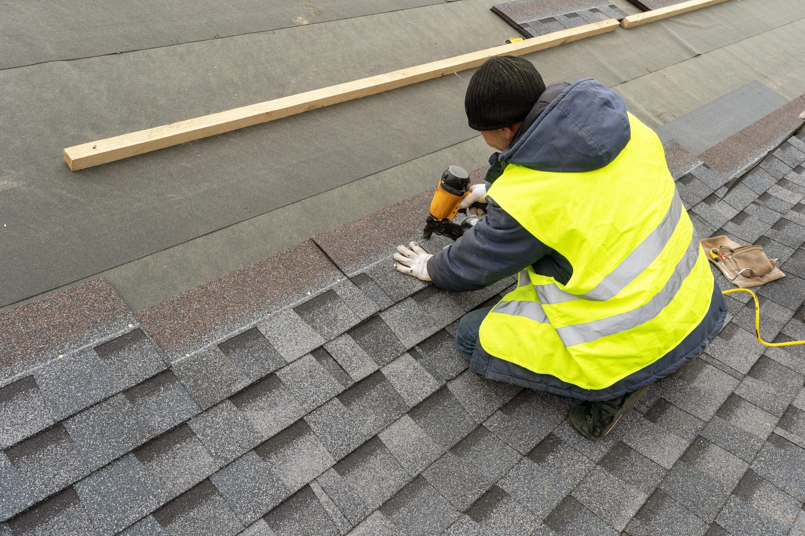 Roofer nailing shingles to a roof